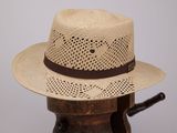 un chapeau de paille posé sur un support en bois, sur lequel se trouve un chapeau