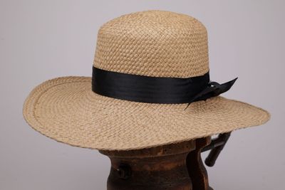 une image représentant un chapeau de paille orné d'un ruban noir
