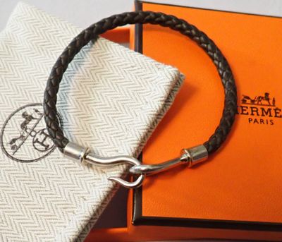 une boîte orange avec un bracelet en cuir noir et un fermoir en argent
