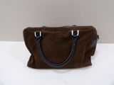 brown sued handbag with black leather handles on a white surface