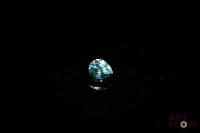 a close up of a blue diamond on a black surface