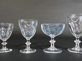 four glass goblets are lined up on a black surface