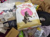 a bag of cat food sitting on top of a pile of other items