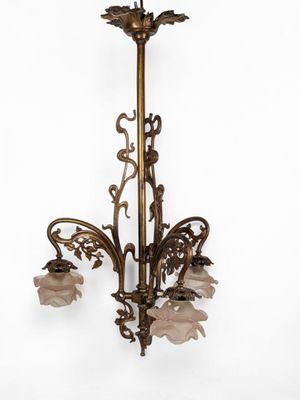 un lustre en laiton orné de fleurs en verre rose suspendu au plafond
