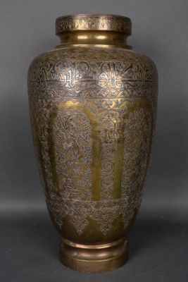 un vase ancien en laiton sur fond gris avec un fond noir