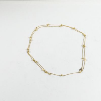 un collier en or orné d'une pierre noire sur un fond blanc