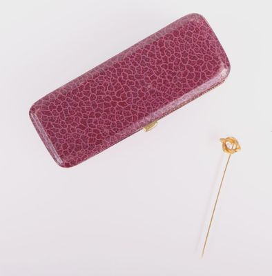 purple leather case with a gold pin on a white background