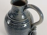 a blue vase with a handle on a white surface