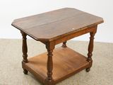 an old wooden table with a shelf underneath it on a carpeted floor