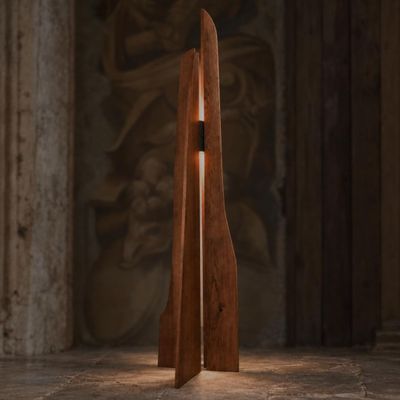 une sculpture en bois d'où émane une lumière dans une pièce sombre