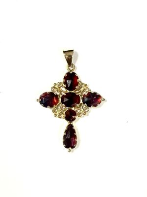 a close up of a cross pendant with garnets on a white background