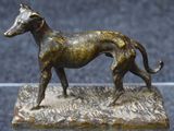 statue en bronze représentant un chien, posée sur un socle posé sur une table