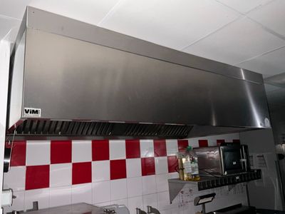 une grande hotte en acier inoxydable dans une cuisine aux carreaux à damier rouges et blancs