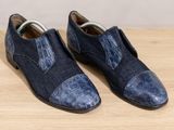 pair of men ' s shoes on a wooden table with a white wall in the background