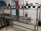 a stainless steel work bench in a kitchen with black and white tiles