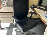 a black office chair sitting in front of a computer desk