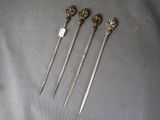 four antique silverware spoons with ornate handles on a gray surface