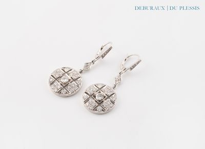 une paire de boucles d'oreilles ornées de diamants, posées sur un fond blanc