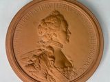 une image représentant une médaille de bronze sur laquelle figure une femme de profil