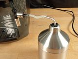 a silver coffee grinder sitting on a wooden table next to a computer