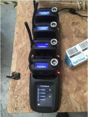 Plusieurs téléphones portables sont alignés sur une table, à côté d'une boîte de piles.