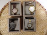 trois boîtes contenant quatre montres différentes, posées sur une table