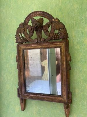 a mirror hanging on a green wall with a wooden frame