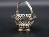 an antique silver basket with a handle on a black surface