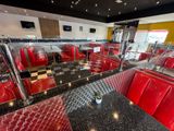 tables and booths in a diner with red leather seats and checkered flooring