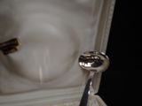 a silver spoon in a white box with a black handle