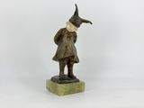 statue d'un homme coiffé d'un chapeau et vêtu d'un manteau, debout sur un socle en marbre