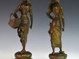 pair of bronze figurines of a woman and a man holding baskets