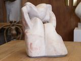 une sculpture en marbre blanc posée sur une table, avec une horloge en arrière-plan