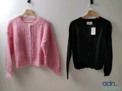 des pulls roses et noirs suspendus à un cintre sur un mur blanc