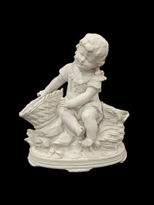 statue d'un garçon assis sur une pile de livres, tenant un panier