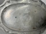 a silver plate with a bird on it on a table