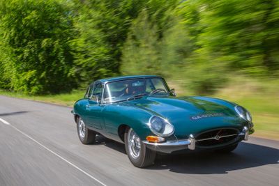 a green car driving down the road with trees in the background