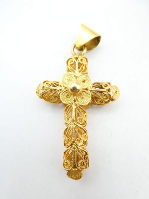 a gold cross pendant with filigree design on a white background