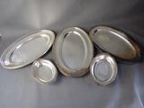 many silver plates on a table with a vase in the background