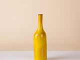 yellow glass bottle on a white table against a beige background