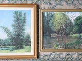 two paintings of trees are hanging on a wall in a room