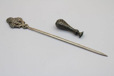 un petit objet en métal muni d'une poignée et un petit objet en métal orné d'une fleur