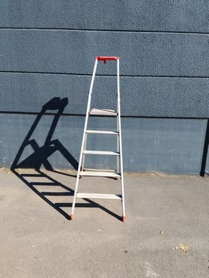 une échelle appuyée contre un mur, sur laquelle se projette une ombre