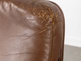 a close up of a brown leather chair with a remote control
