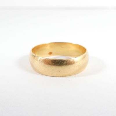 gros plan d'une bague en or sur une surface blanche