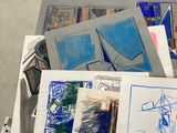 a pile of drawings on the floor next to a pile of books