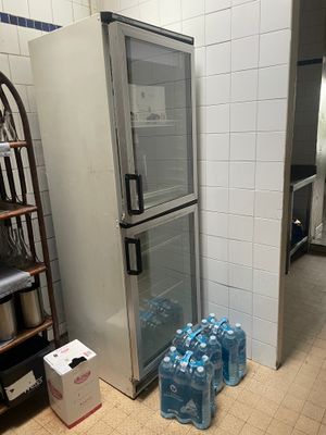 des bouteilles d'eau sont posées devant un réfrigérateur ouvert dans une cuisine