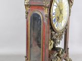 a red and gold clock sitting on a white surface