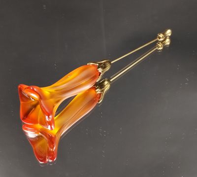 orange and yellow flower shaped glass broochle on a black surface