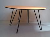 a wooden table with black hairpin legs on a white floor